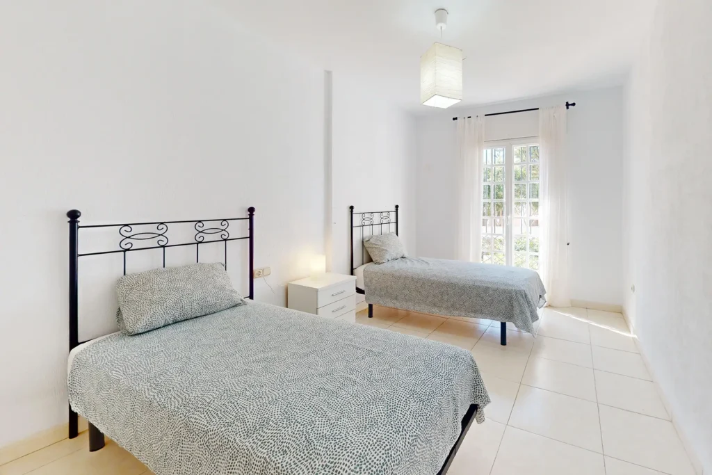 Dormitorio con dos camas individuales y salida al exterior en chalet pareado en Rota