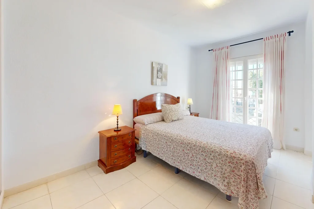Dormitorio luminoso con cama de matrimonio y balcón en chalet pareado en Rota