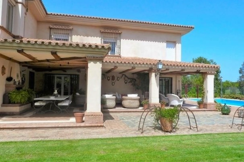 Fachada con porche, jardín y piscina en chalet en venta en Dehesa Golf, Huelva