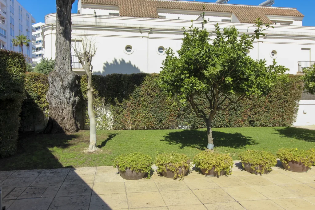 Jardín privado con árboles y zona pavimentada en chalet pareado en Rota